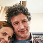 Un homme et une femme souriant ensemble, posant pour une photo en intérieur.